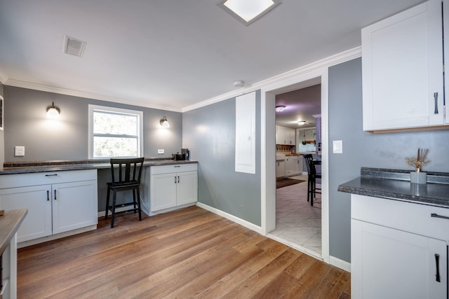 kitchen featuring white cabinetry, ornamental molding, and light wood-type flooring