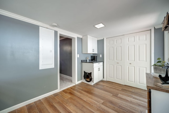 interior space featuring ornamental molding, light hardwood / wood-style flooring, and white cabinets