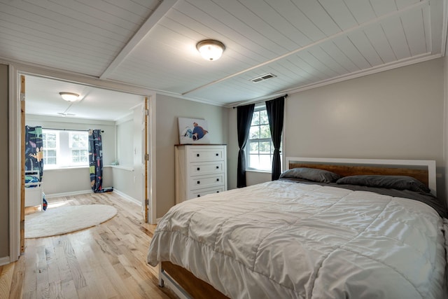 bedroom featuring light hardwood / wood-style floors, crown molding, and multiple windows