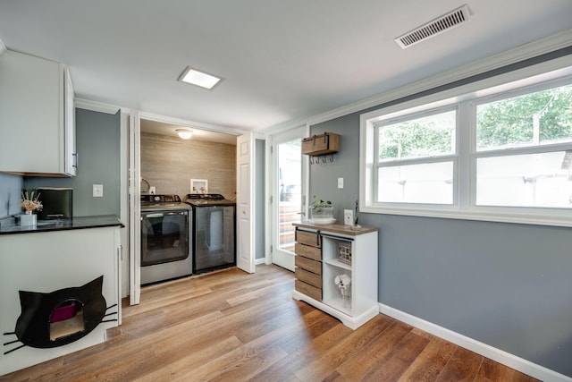 kitchen with white cabinetry, light hardwood / wood-style floors, ornamental molding, and washing machine and clothes dryer