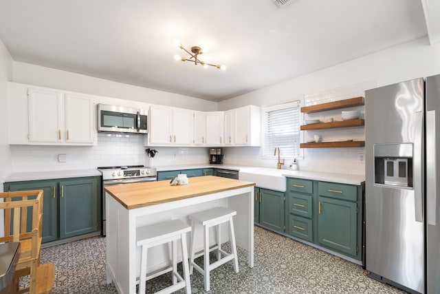 kitchen featuring tasteful backsplash, appliances with stainless steel finishes, sink, a center island, and white cabinets