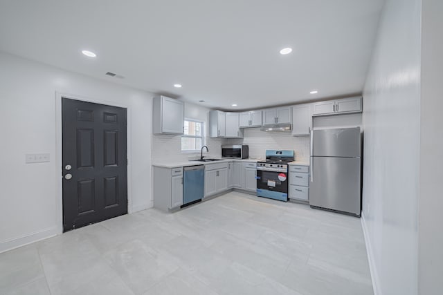 kitchen featuring appliances with stainless steel finishes, sink, backsplash, and gray cabinetry