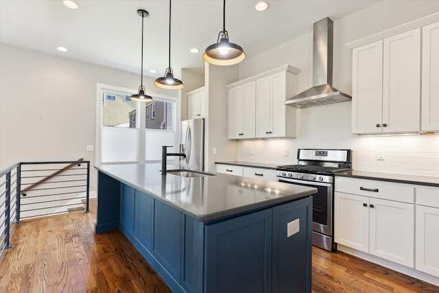 kitchen featuring wall chimney range hood, dark wood-type flooring, hanging light fixtures, white cabinetry, and appliances with stainless steel finishes