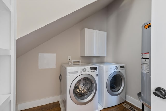 washroom featuring cabinets, water heater, washing machine and clothes dryer, and dark hardwood / wood-style flooring