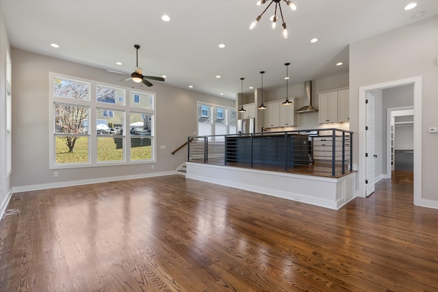 unfurnished living room featuring ceiling fan with notable chandelier and dark hardwood / wood-style flooring