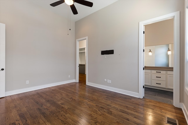 unfurnished bedroom with a walk in closet, dark wood-type flooring, and ceiling fan