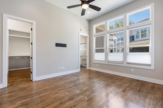 unfurnished bedroom with dark hardwood / wood-style flooring, a spacious closet, and ceiling fan