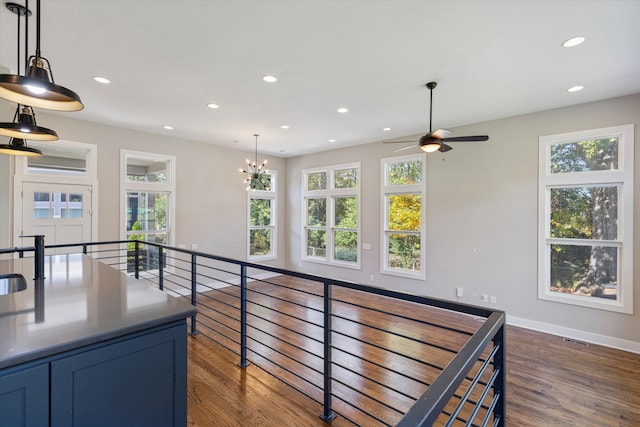 kitchen with dark wood-type flooring, decorative light fixtures, and ceiling fan with notable chandelier