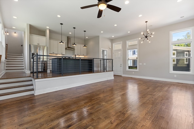 unfurnished living room featuring dark hardwood / wood-style flooring and ceiling fan with notable chandelier