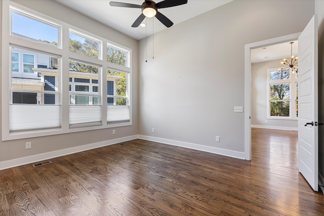 unfurnished room with dark hardwood / wood-style floors and ceiling fan with notable chandelier