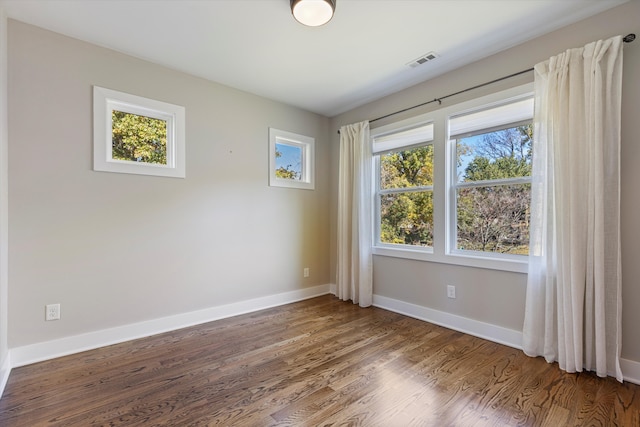 spare room with dark wood-type flooring and plenty of natural light