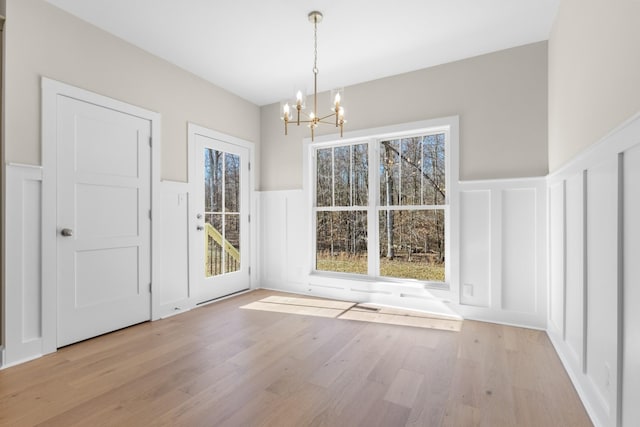 unfurnished dining area with light wood-type flooring and a chandelier