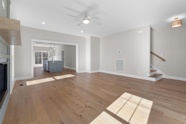 unfurnished living room featuring ceiling fan, wood-type flooring, and sink