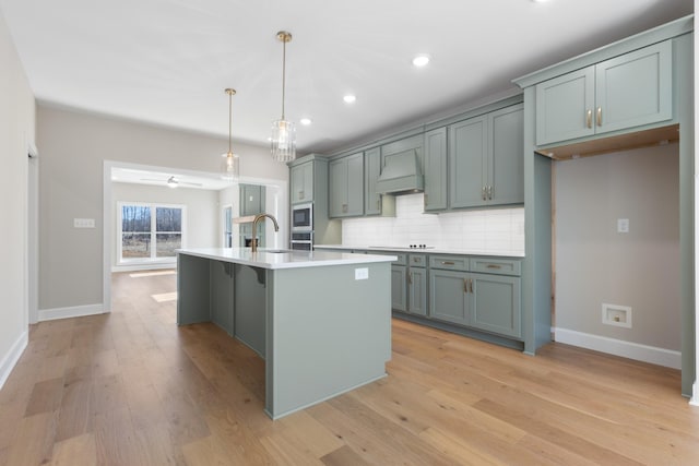 kitchen featuring premium range hood, decorative light fixtures, an island with sink, decorative backsplash, and stainless steel appliances