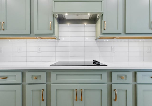 kitchen featuring black electric cooktop, premium range hood, green cabinets, and backsplash