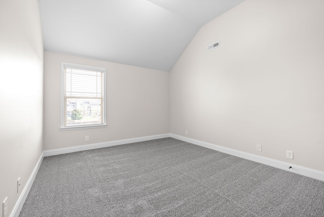 carpeted spare room featuring vaulted ceiling