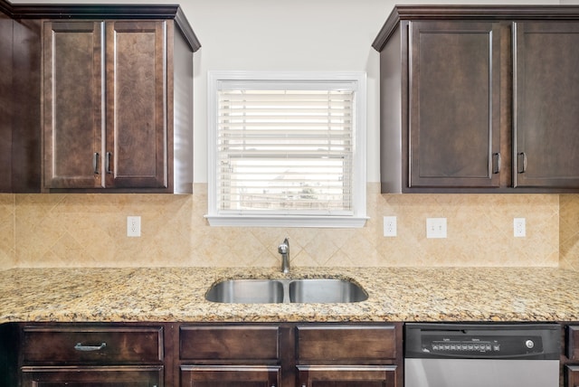 kitchen featuring backsplash, stainless steel dishwasher, sink, and light stone counters