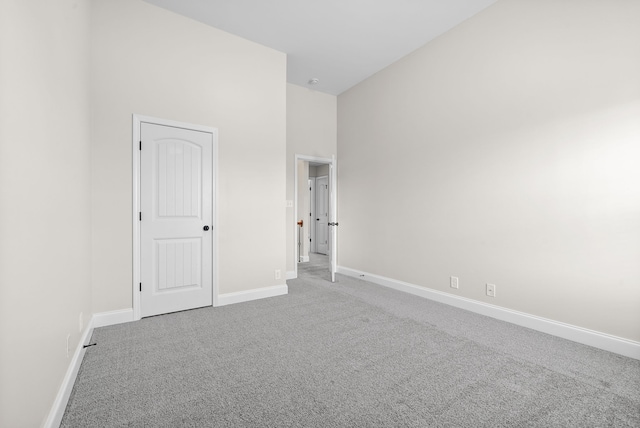 carpeted spare room featuring a high ceiling