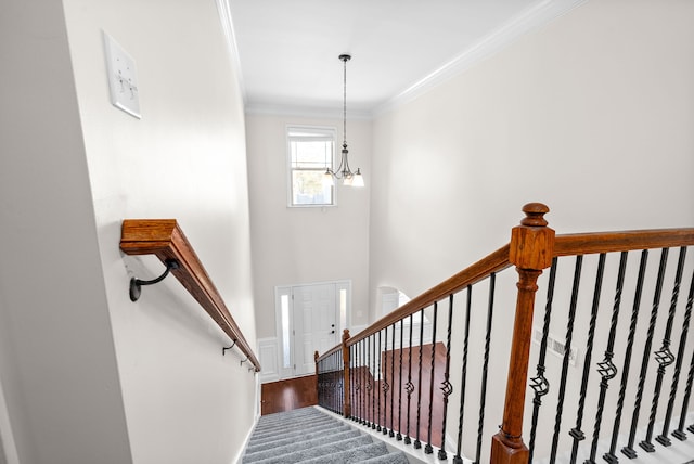 stairway featuring an inviting chandelier, ornamental molding, and wood-type flooring