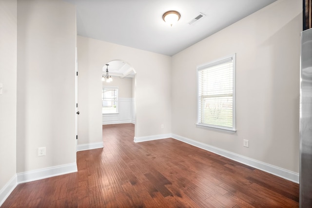 spare room with an inviting chandelier and hardwood / wood-style floors