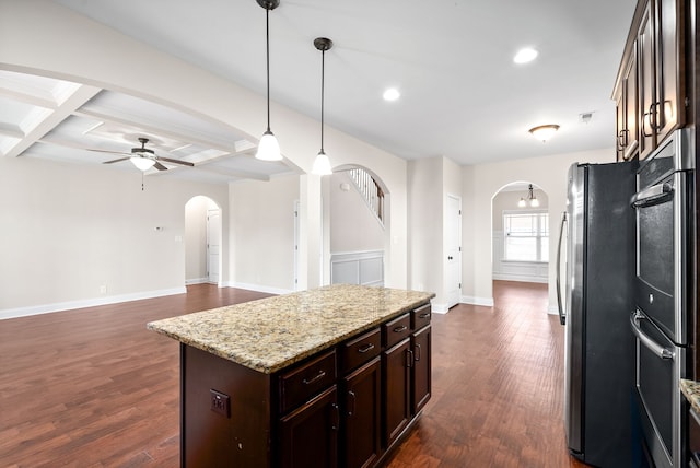 kitchen featuring stainless steel fridge, dark brown cabinetry, pendant lighting, light stone countertops, and dark wood-type flooring