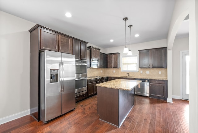 kitchen featuring stainless steel appliances, hanging light fixtures, dark hardwood / wood-style floors, and a center island