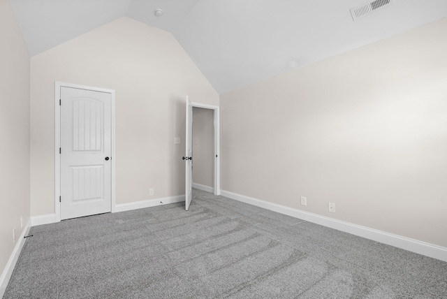 carpeted empty room with lofted ceiling