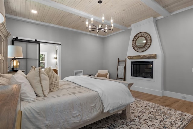 bedroom featuring hardwood / wood-style flooring, beamed ceiling, wooden ceiling, a barn door, and an inviting chandelier