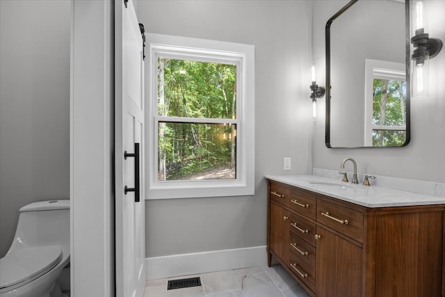 bathroom featuring toilet, a healthy amount of sunlight, and vanity