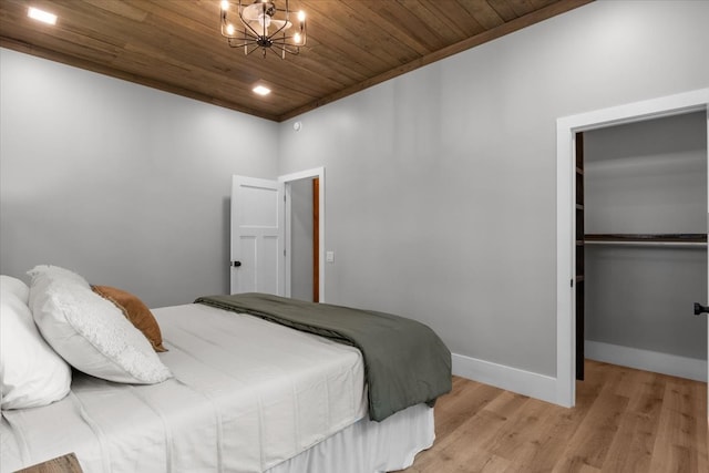 bedroom with wood ceiling, a walk in closet, a chandelier, light hardwood / wood-style flooring, and a closet