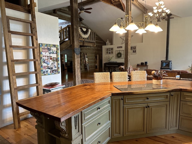 kitchen with black electric stovetop, light hardwood / wood-style floors, a wood stove, wooden counters, and a center island