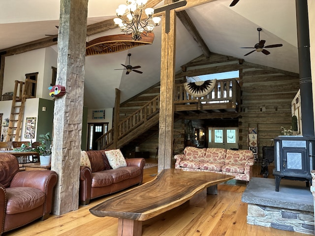 living room featuring light hardwood / wood-style flooring, high vaulted ceiling, and a wood stove