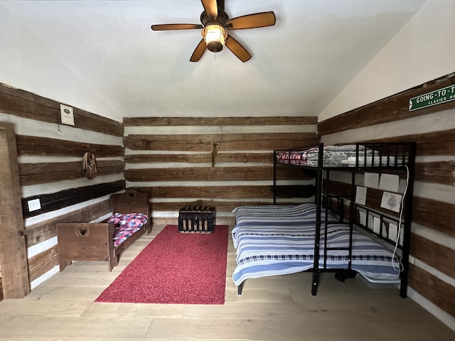 bedroom featuring vaulted ceiling, ceiling fan, hardwood / wood-style flooring, and wood walls