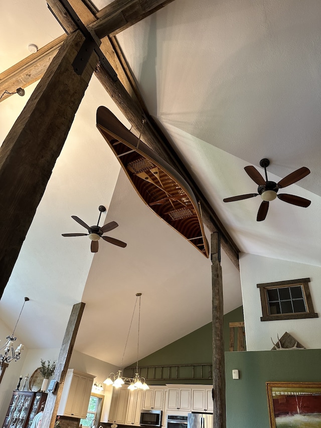 room details featuring cream cabinets, beam ceiling, appliances with stainless steel finishes, ceiling fan with notable chandelier, and pendant lighting