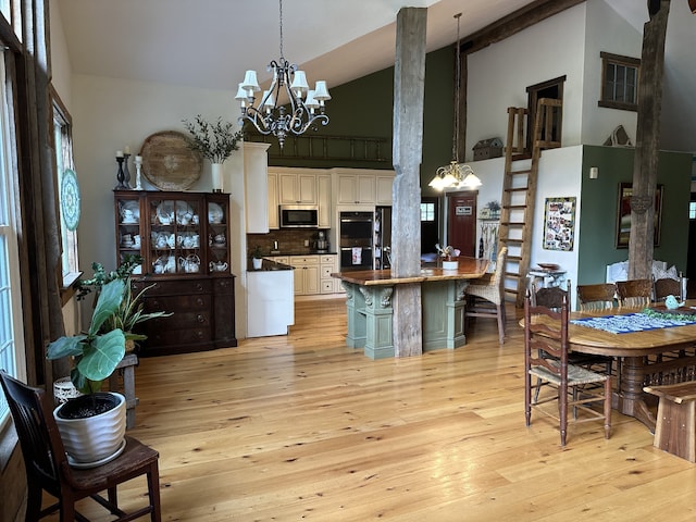 kitchen featuring hanging light fixtures, white cabinetry, high vaulted ceiling, light wood-type flooring, and double oven