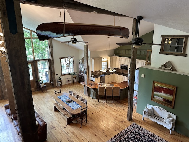 dining space featuring light hardwood / wood-style flooring, lofted ceiling with beams, and ceiling fan with notable chandelier