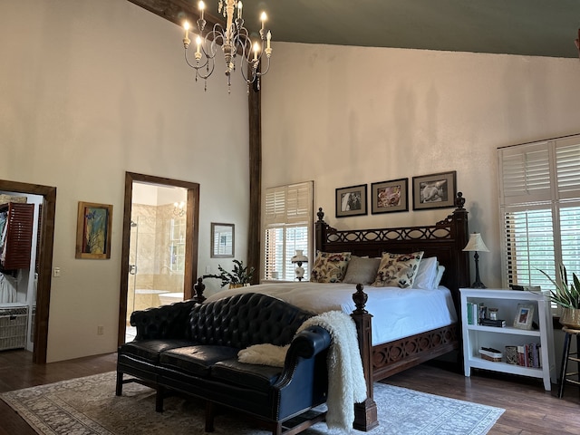 bedroom with dark wood-type flooring, ensuite bath, a towering ceiling, and a chandelier