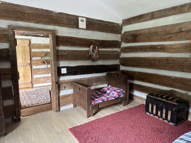 bedroom with lofted ceiling, wood walls, and light wood-type flooring