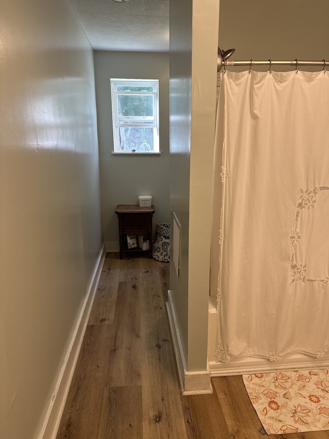 bathroom with a textured ceiling, shower / bath combination with curtain, and hardwood / wood-style flooring