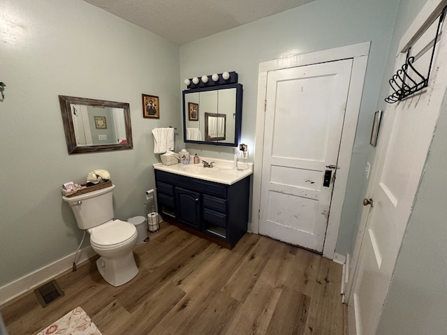 bathroom featuring vanity, a textured ceiling, wood-type flooring, and toilet