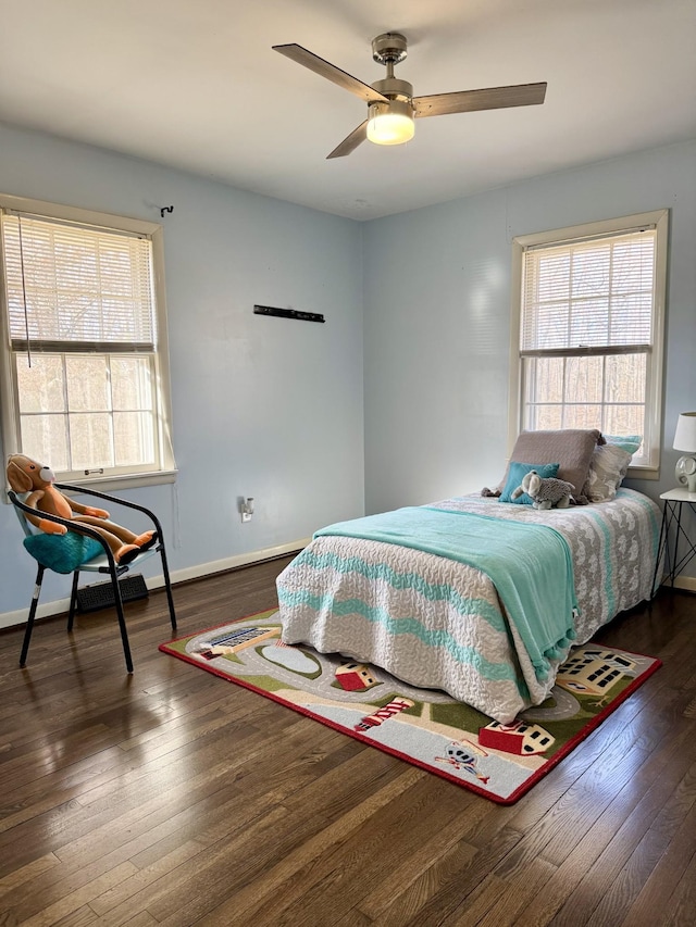 bedroom with ceiling fan, dark wood-type flooring, and multiple windows