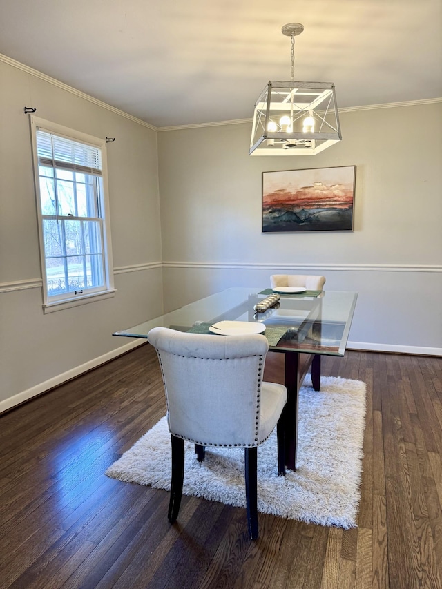 dining room featuring dark wood-type flooring, ornamental molding, and a chandelier