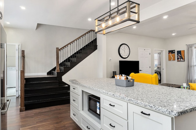 kitchen featuring dark wood-type flooring, white cabinets, black microwave, and decorative light fixtures