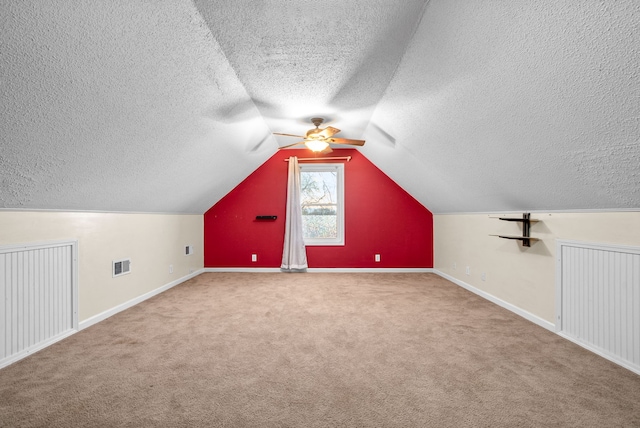 bonus room featuring vaulted ceiling, ceiling fan, carpet flooring, and a textured ceiling