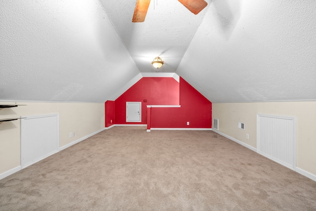 additional living space featuring ceiling fan, light colored carpet, lofted ceiling, and a textured ceiling