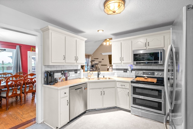 kitchen with backsplash, sink, light hardwood / wood-style floors, and appliances with stainless steel finishes