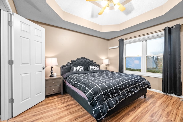 bedroom with a raised ceiling, ceiling fan, and hardwood / wood-style floors