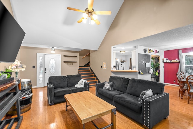 living room featuring ceiling fan, light hardwood / wood-style floors, and high vaulted ceiling