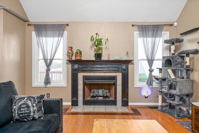 living room featuring a tile fireplace, wood-type flooring, and lofted ceiling