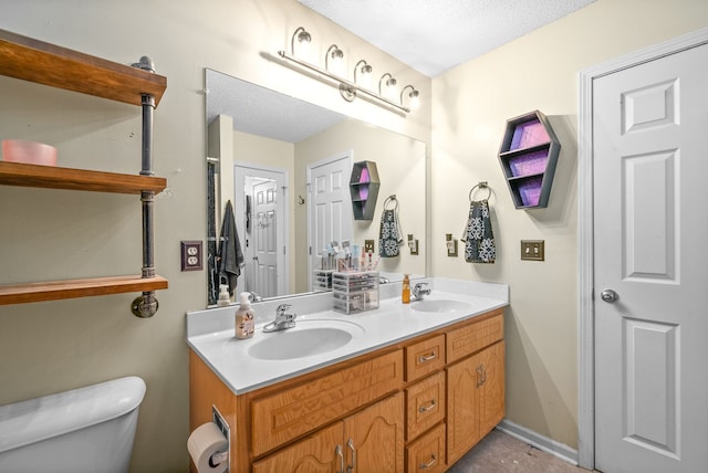 bathroom with vanity, toilet, and a textured ceiling